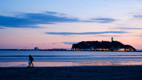 Silhouette man standing on beach against sky during sunset