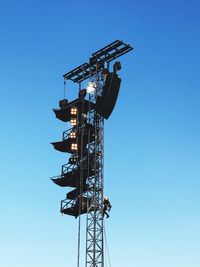 Low angle view of floodlight tower against clear blue sky