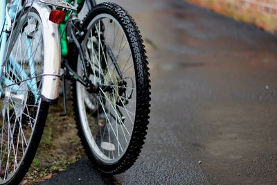 Cropped image of bicycle wheels on wet road