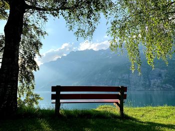 Empty bench in park against mountains