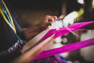 Midsection of woman working with threads in textile factory