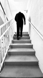 Rear view of man walking on staircase