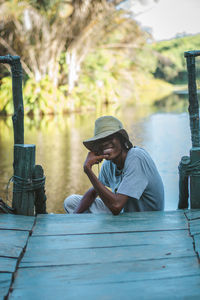 Young adult tourist sitting on a wooden material against lake view