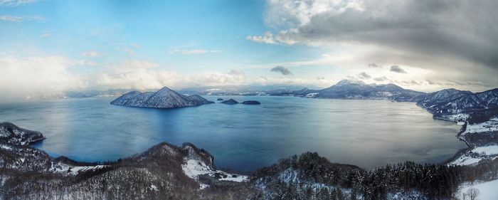 Scenic view of sea and snowcapped mountains against sky