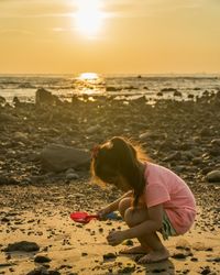 Side view of girl playing at beach during sunset