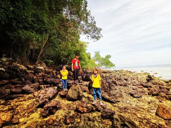 People standing on rock against sky