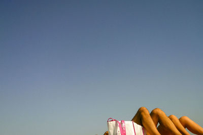 Low angle view of hand against clear blue sky in the beach