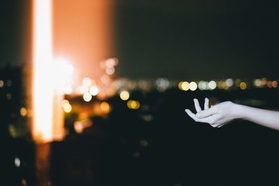 Cropped hand of woman in illuminated city