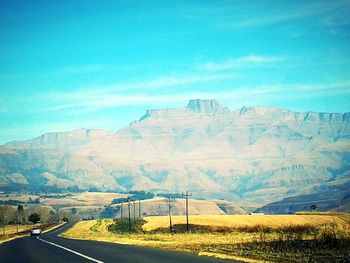 Road by landscape against blue sky