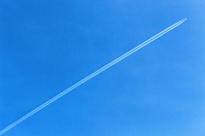 Low angle view of vapor trail in blue sky