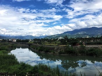 High angle view of pond with trees and clouds reflection