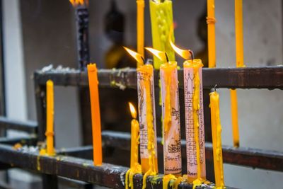 Close-up of lit candles in temple against building