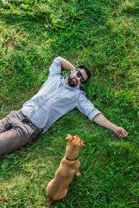 Man and dog lying on green grass in summer, top view. attractive european man resting with his dog.
