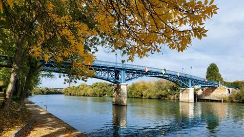 Bridge over river against sky during autumn