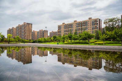 Reflection of buildings and trees in lake against sky