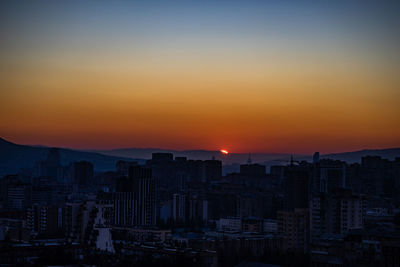 Sunrise time over tbilisi's downtown with bright blue sky and red sun
