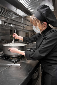 Side view of woman standing in kitchen