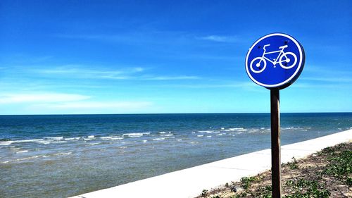 Information sign on beach against blue sky