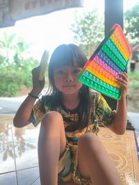 Portrait of happy girl sitting on multi colored background
