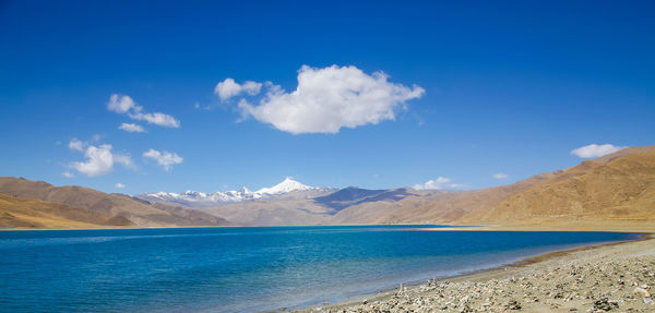 Scenic view of sea and mountains against blue sky