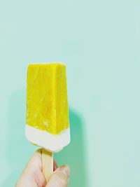 Cropped hand holding ice cream cone against clear sky