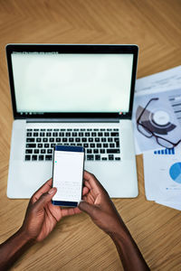 Cropped hands of man using laptop on table