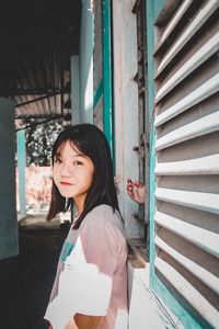 Portrait of smiling young woman standing against built structure