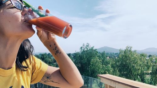 Midsection of woman holding plants against sky