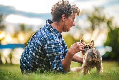 Side view of senior woman playing with dog in park