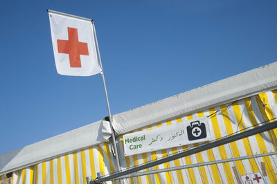 Red cross flag on an aid station, clear blue sky