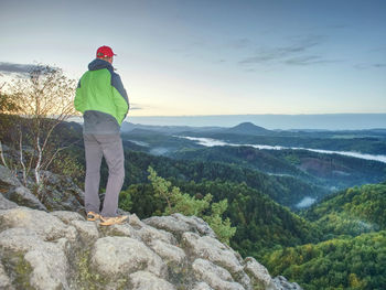 Man stands alone on the peak of rock. hiker watching to autumn sun at horizon . beautiful moment