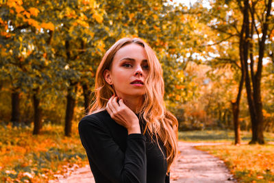 Portrait of young woman with blonde hair in autumn golden park. autumn concept. fall leaves