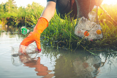 Low section of woman cleaning lake