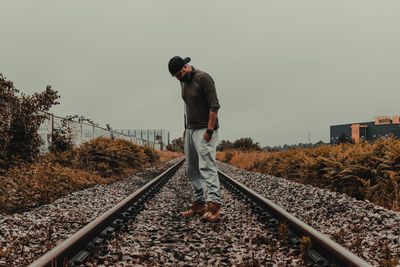 Man standing on railroad track against sky