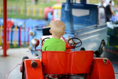 Rear view of boy sitting in toy car