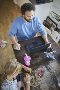 Man working from home while daughter counting savings