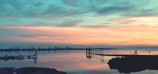 Silhouette pier over sea against sky during sunset