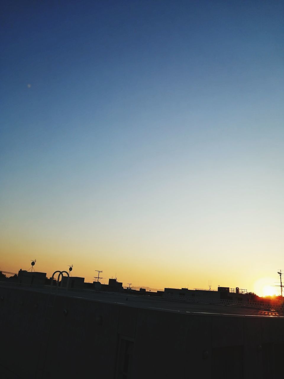 SILHOUETTE BUILDINGS AGAINST CLEAR SKY DURING SUNSET IN CITY