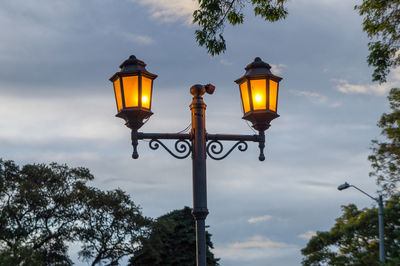 Low angle view of illuminated street light against sky