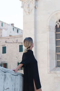 Side view of woman standing by building