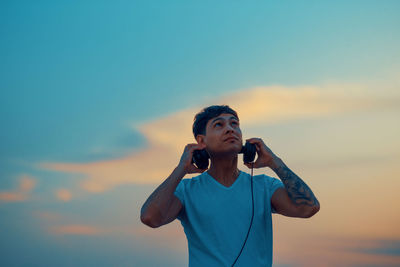 Portrait of young handsome man wearing headphones during sunset