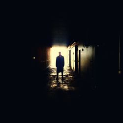 Silhouette of man walking in illuminated corridor