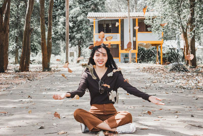 Portrait of smiling young woman sitting on plant