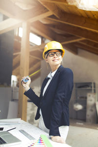 Architect wearing hardhat while working at construction site