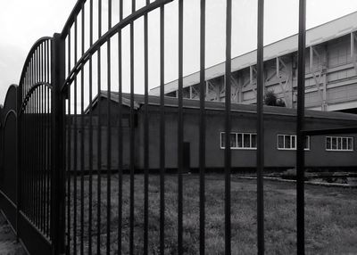 Building by fence against sky