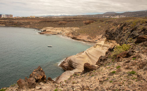 Scenic view of sea and rocky mountains against sky