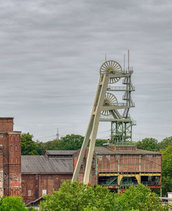 Traditional windmill by building against sky