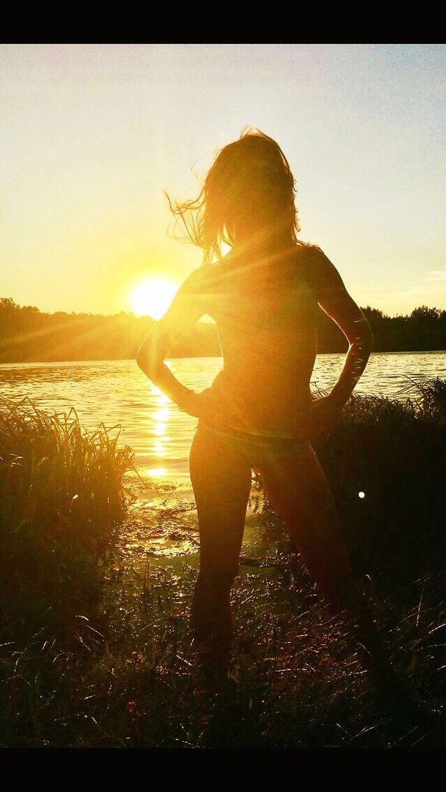 REAR VIEW OF SILHOUETTE WOMAN STANDING BY LAKE AGAINST SKY