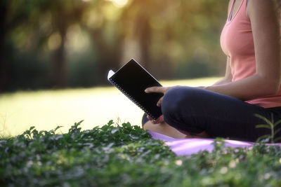 Side view of woman using mobile phone on field