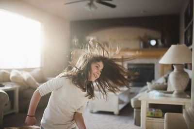 Smiling girl tossing hair while standing in living room